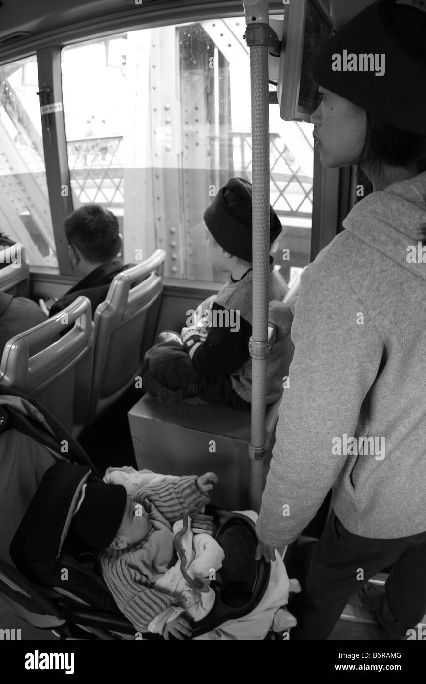 Giovane madre con due bambini sul servizio pubblico di autobus di città in Cina Guanjgzhou durante la crisi economica mondiale; chinas uno bambini Foto Stock