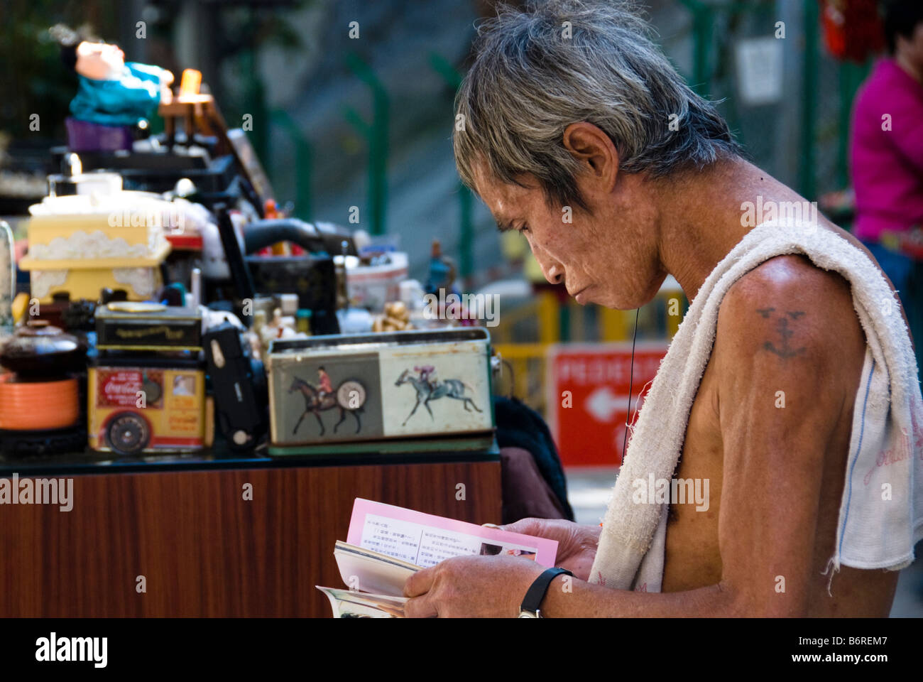 Il vecchio uomo cinese legge un libro usato in Cat Street (Laskar riga), il mercato di Hong Kong Foto Stock