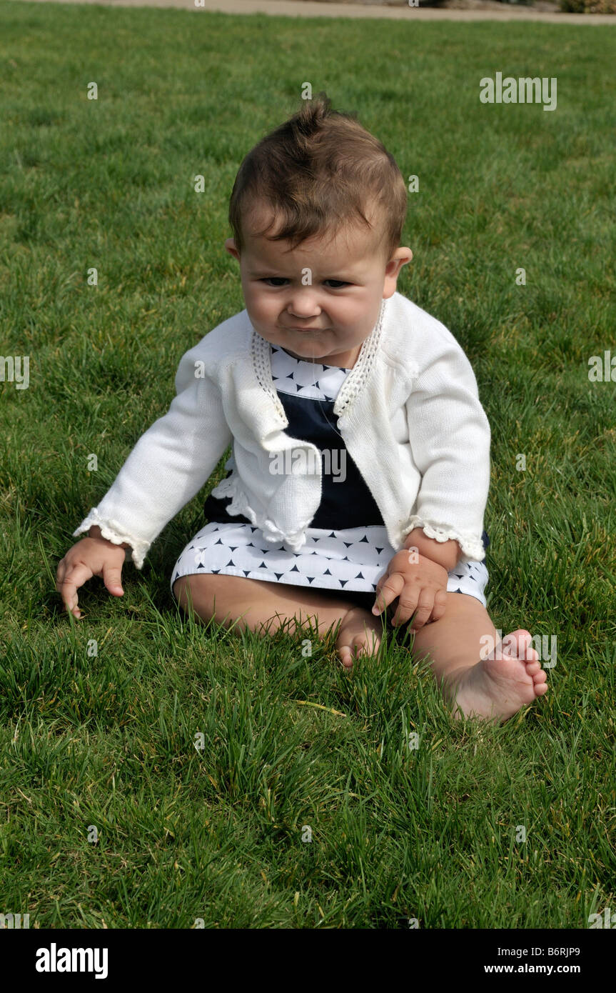 Poco American baby ragazza seduta sul prato Foto Stock