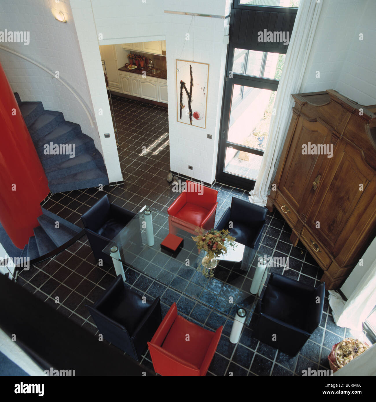 Birdseye vista del tavolo di vetro e il rosso e il nero le sedie in pelle nella hall moderna sala da pranzo con Black piastrelle per pavimento Foto Stock
