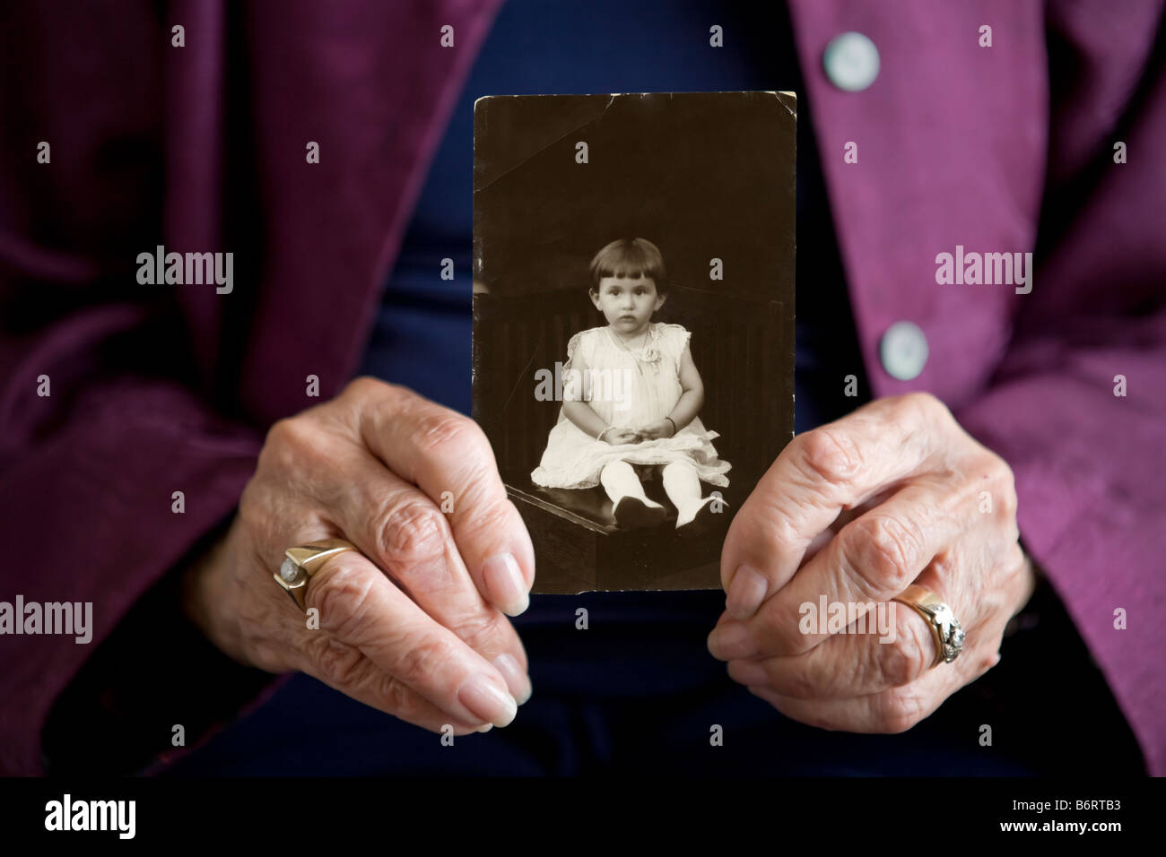 Donna anziana tenendo una foto di se stessa quando era un bambino. Stretto prodotto sulle mani solo. Foto Stock