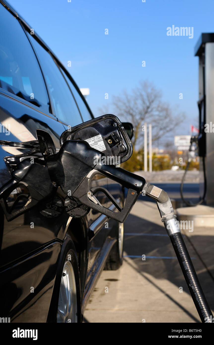 Pompa a gas ugello inserito in un auto nera durante il rifornimento di carburante in una stazione di benzina in inverno canadese Toronto Foto Stock