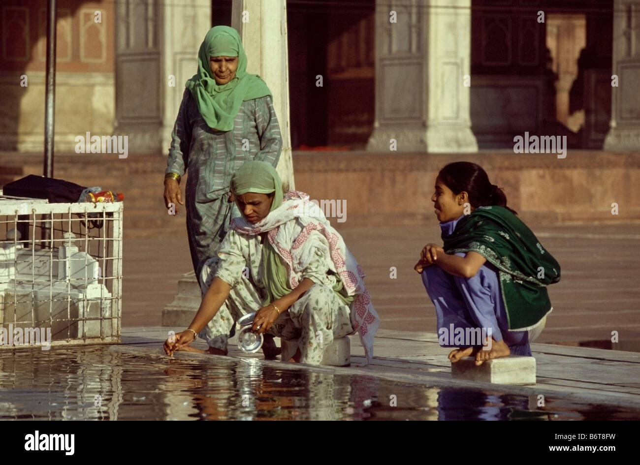 Tre povere donne che prendono acqua dal serbatoio nella grande moschea ( Jama Masjid ) nella Vecchia Delhi, India Foto Stock