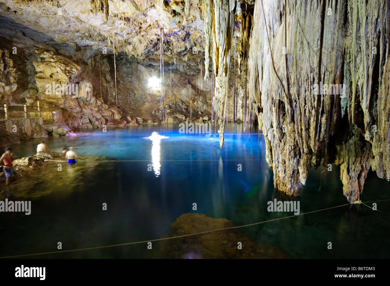 Cenote Xkeken stalactites Valladolid Messico // VALLADOLID, Messico — le stalattiti calcaree pendono dal soffitto del Cenote X'keken (noto anche come Cenote Xkeken), un cenote sotterraneo situato a circa 7 chilometri a sud di Valladolid nello stato di Yucatán. Il cenote fa parte del complesso dei cenote di Dzitnup, che comprende due distinte caverne calcaree sotterranee formate attraverso processi geologici carsici nel corso di millenni. Questi cenotes chiusi servivano come fonti d'acqua sacra per gli antichi Maya, che li consideravano portali a Xibalba, la malavita Maya. Le acque cristalline mantengono un Co Foto Stock