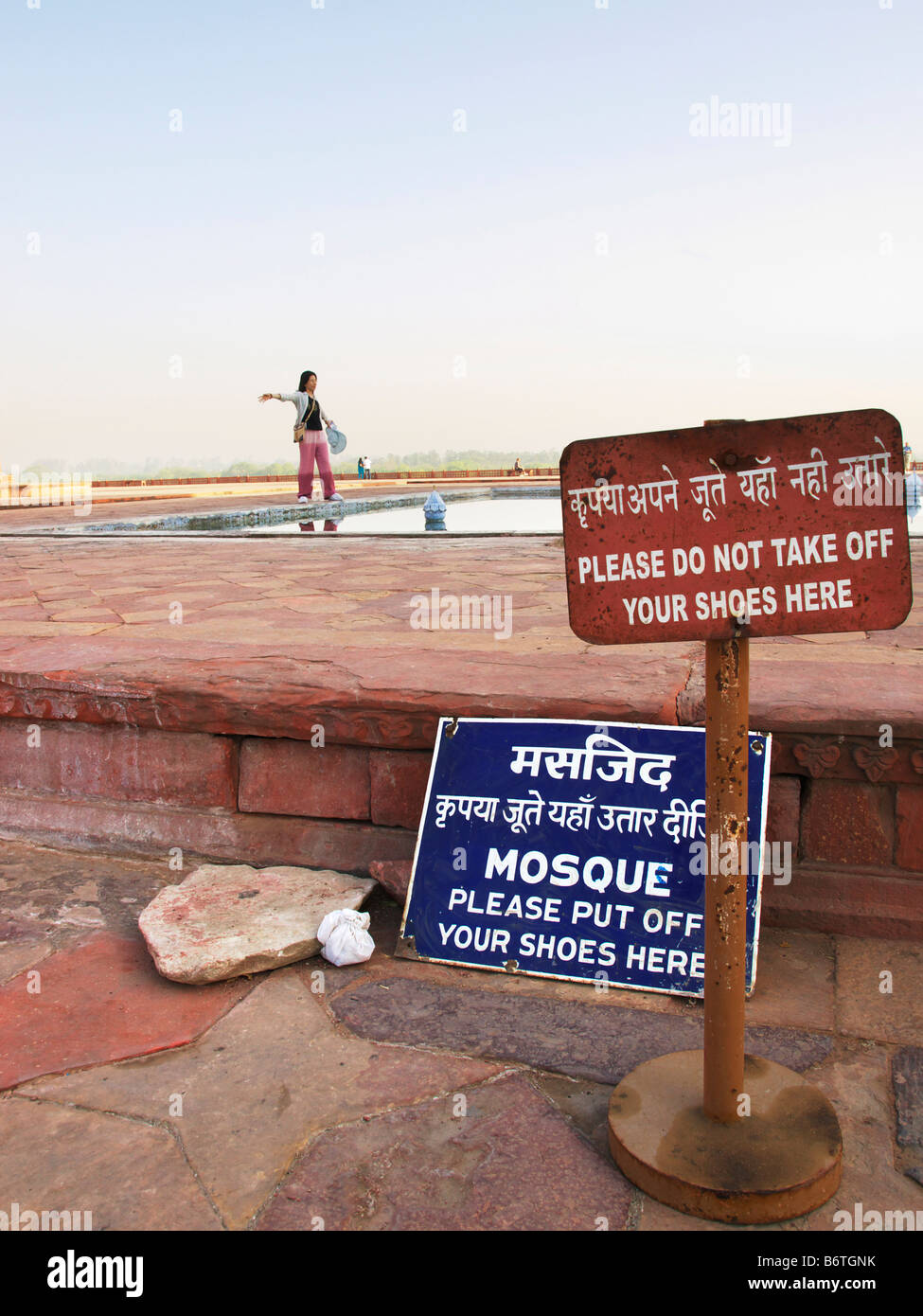 Un turista pone in background, segno whilist Visualizza avviso per togliere le scarpe prima di ingresso al Taj Mahal Foto Stock