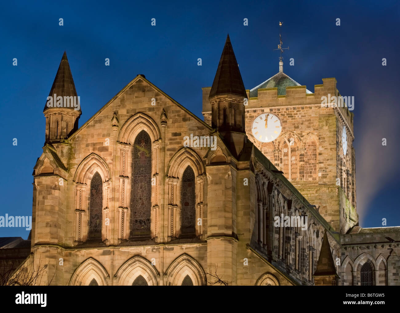 Il diciannovesimo secolo facciata di Saint Andrews (Hexham Abbey) illuminata di notte durante un inverno di crepuscolo, Northumberland, Inghilterra Foto Stock