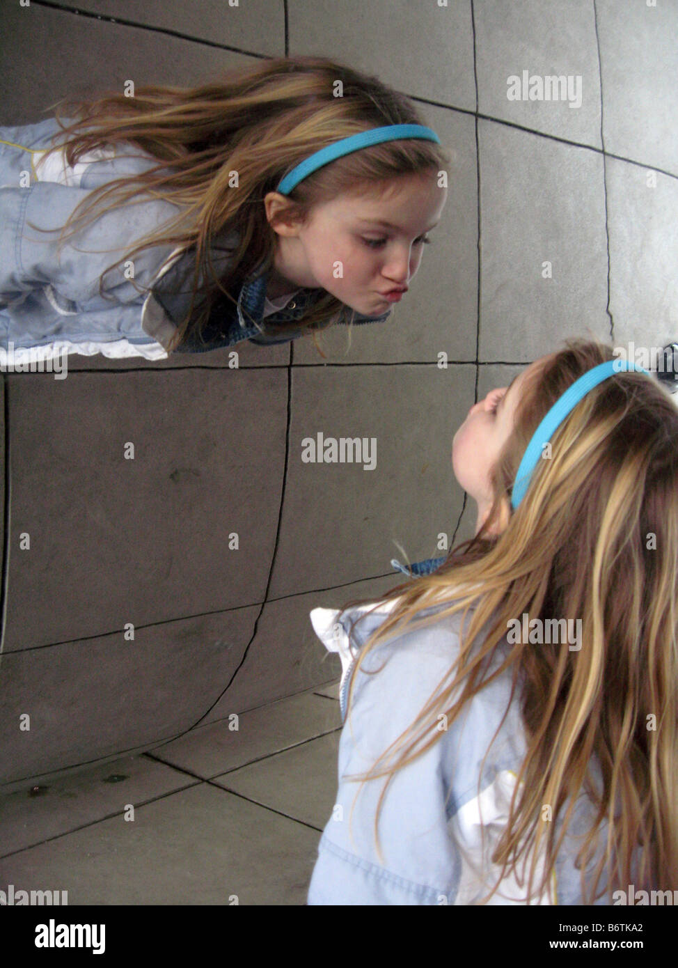 Giovane ragazza guardando il suo riflesso nella scultura di fagiolo in Chicago presso il Millennium Park Foto Stock