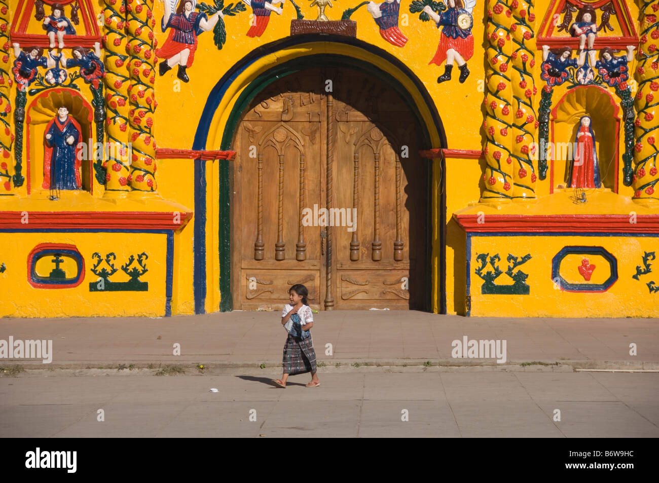 Giovane ragazza di fronte le isole Canarie-giallo chiesa di San Andres Xecul. Guatemala. Foto Stock