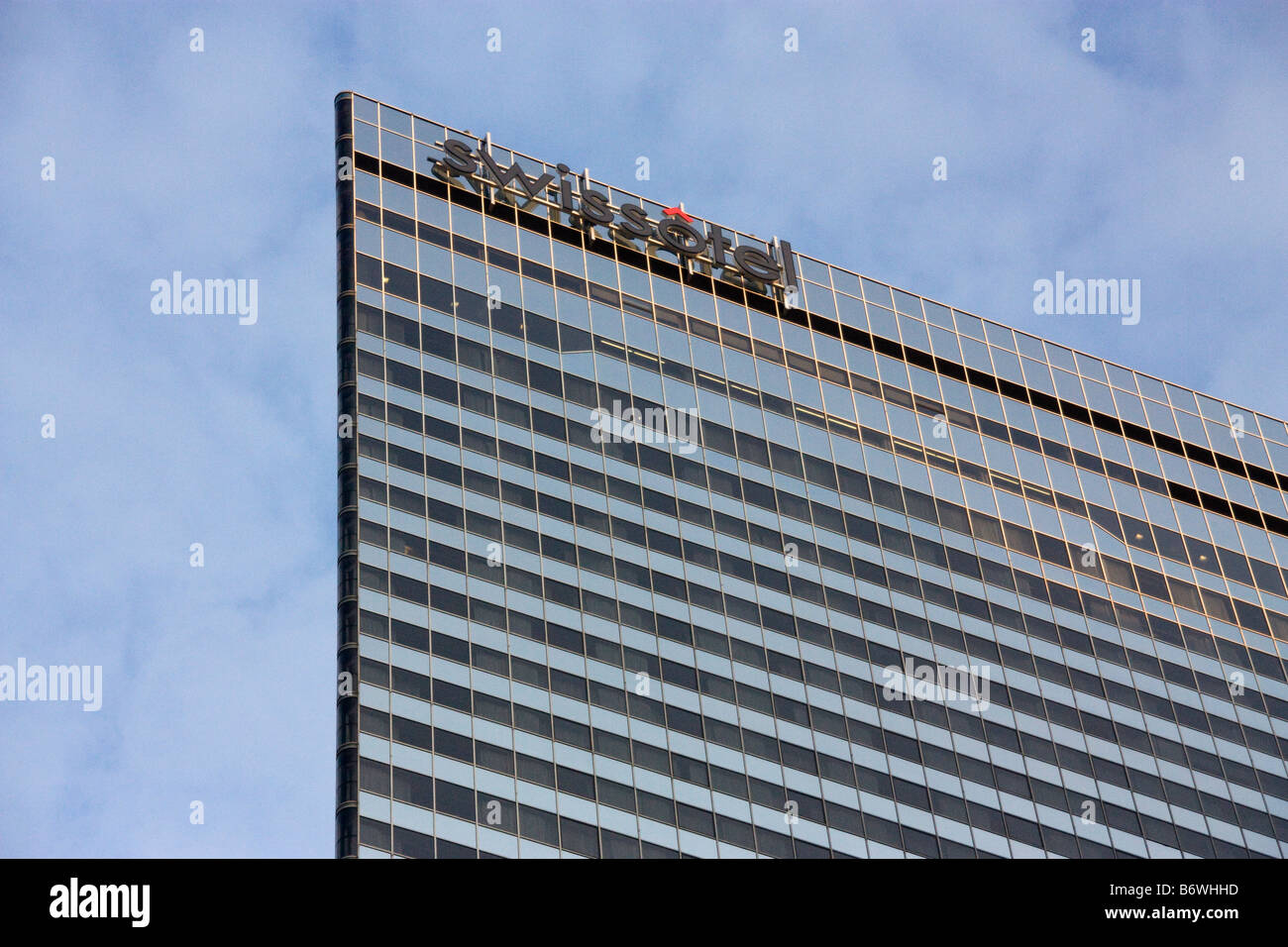 La parte superiore della struttura Swissotel Chicago con nuvole e cielo blu in background Foto Stock