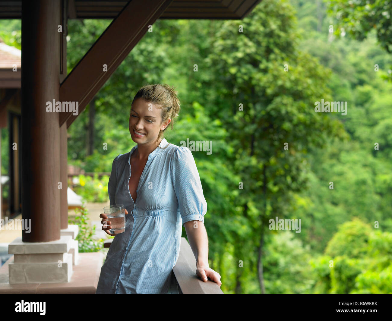 Giovane donna sotto la veranda con vetro di acqua Foto Stock