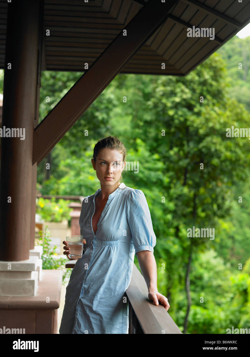 Giovane donna sotto la veranda con vetro di acqua Foto Stock