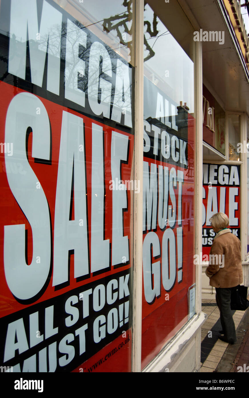 La donna entra in un negozio , le finestre del quale pubblicizzare un mega vendita e che tutte le scorte devono andare in Kingston Surrey, Inghilterra Foto Stock