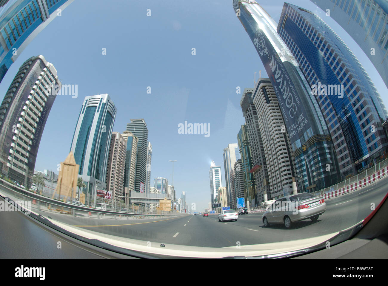 La guida verso il basso principali multi lane road passando per il centro di Dubai foderato con grattacieli immagine Fisheye Foto Stock