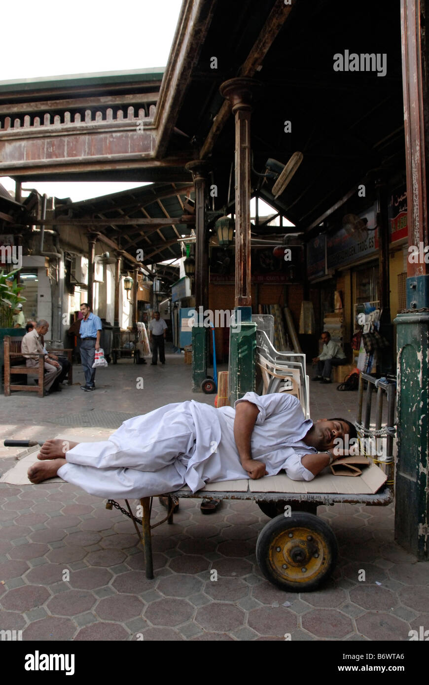 L'uomo addormentato sul carrello in cortile nel souk in città vecchia Dubai Foto Stock
