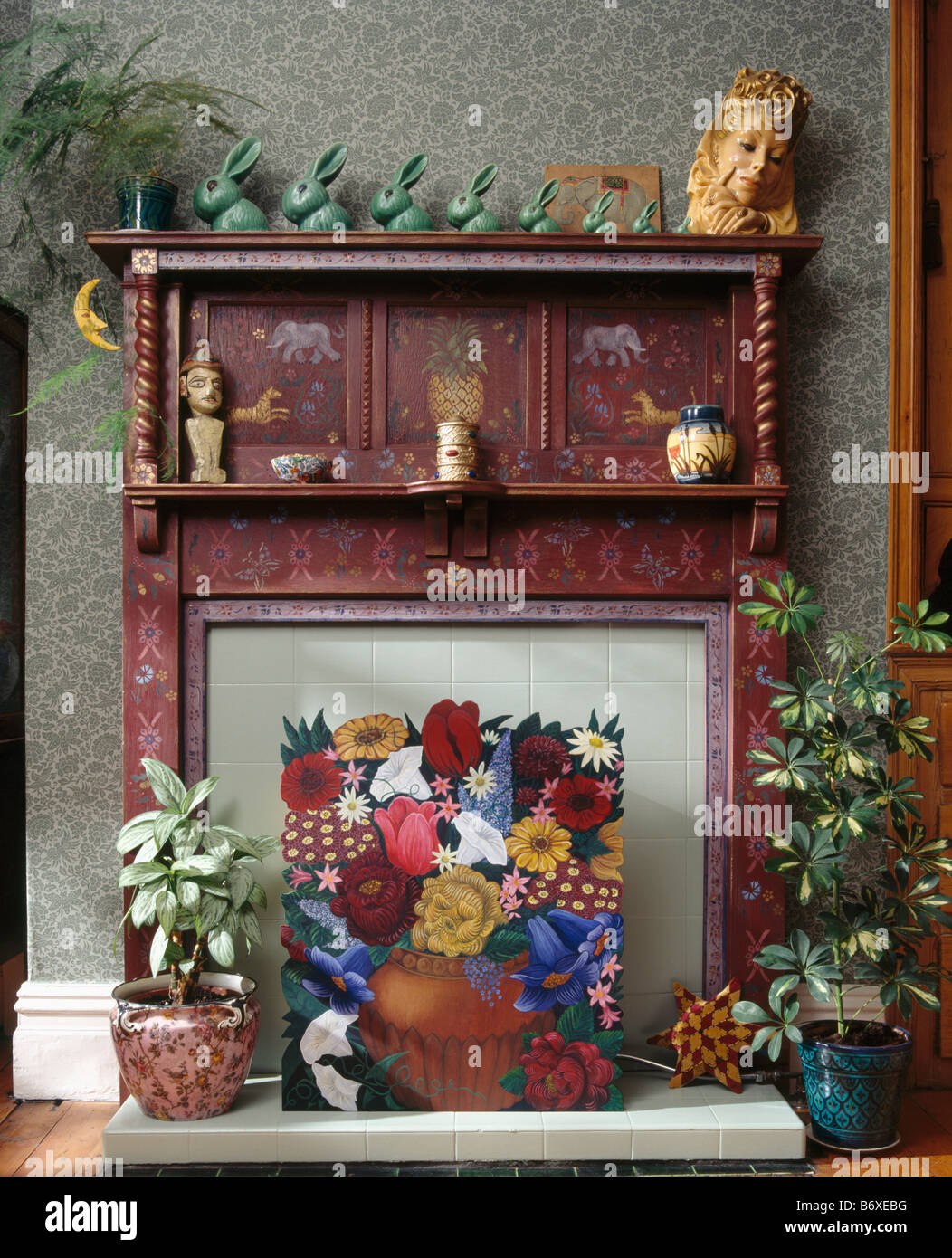 Houseplants e dipinto di floral fire-schermo nella parte anteriore del dipinto di trenta camino con raccolta di verde Denby conigli Foto Stock