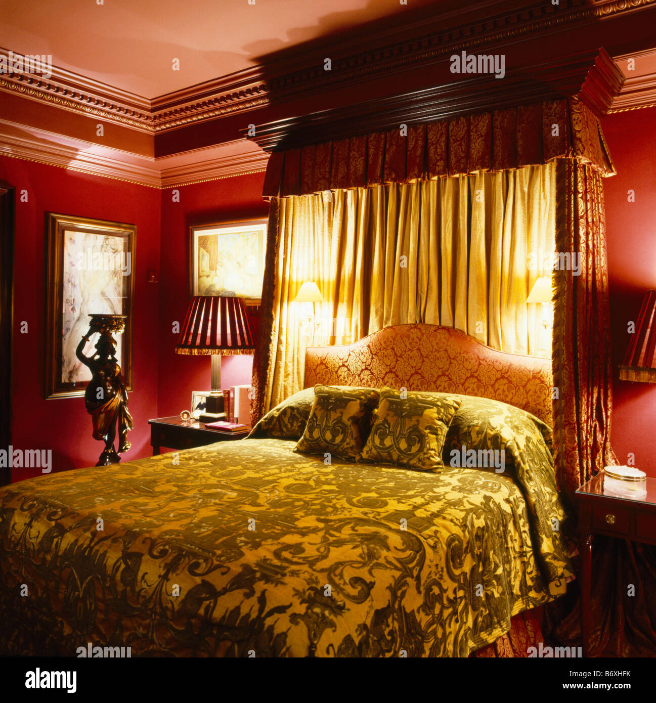 Il velluto bedcover sul tester per metà letto con luci da parete e drappi crema in rosso scuro camera da letto Foto Stock