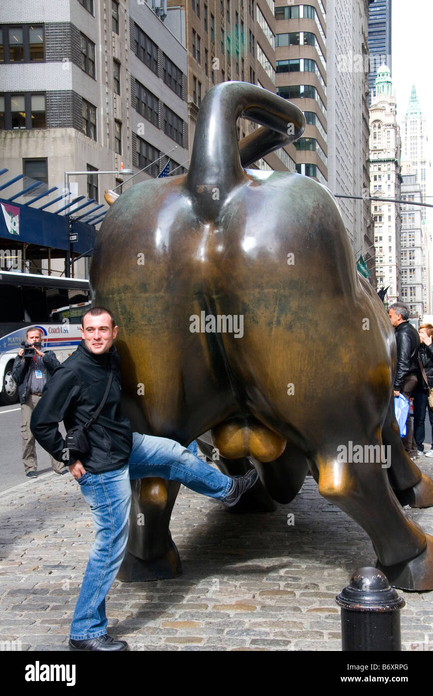 L'uomo avente la sua foto scattata con il Wall Street Bull in Bowling Green park vicino a Wall Street New York City New York STATI UNITI D'AMERICA Foto Stock