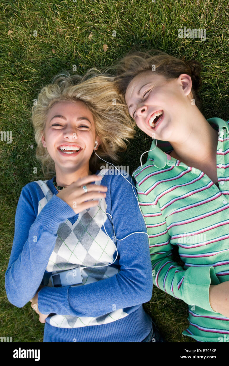 Due ragazze ridere mentre posa in erba ascoltando un ipod, Fort Collins, Colorado. Foto Stock