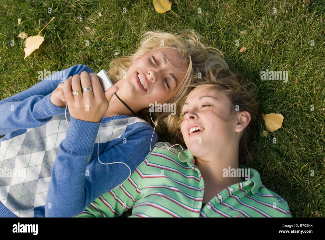 Due ragazze ridere mentre giaceva in erba ascoltando un ipod, Fort Collins, Colorado. Foto Stock