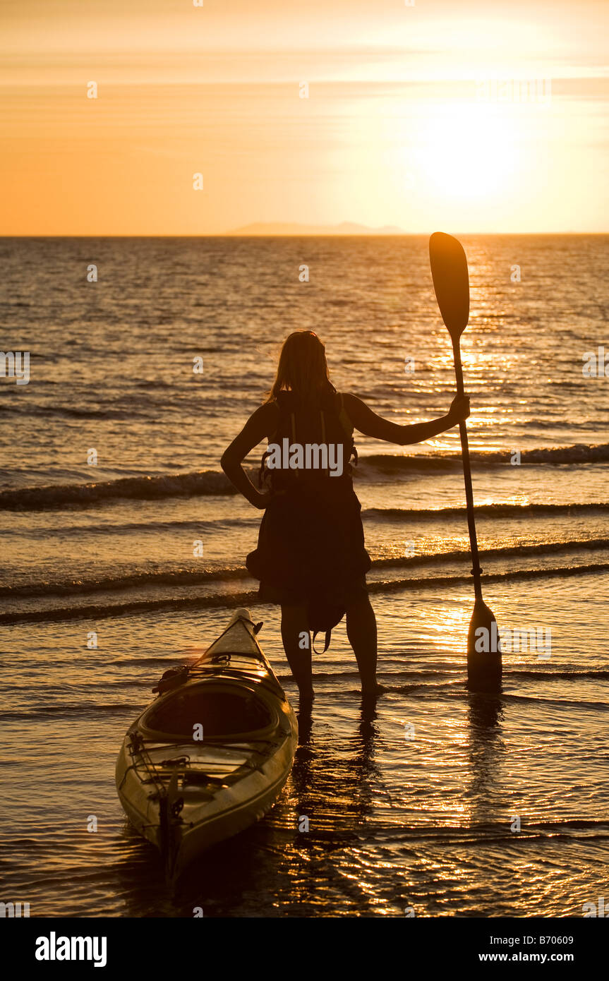Una donna a guardare il tramonto con il suo kayak di mare nella baia di Kino, Messico. Foto Stock
