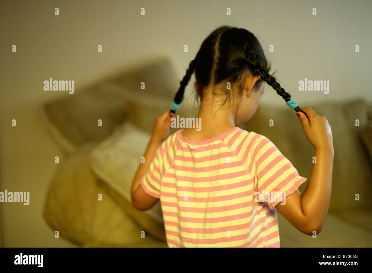 Bambina di cinque anni tira il suo pigtail Foto Stock