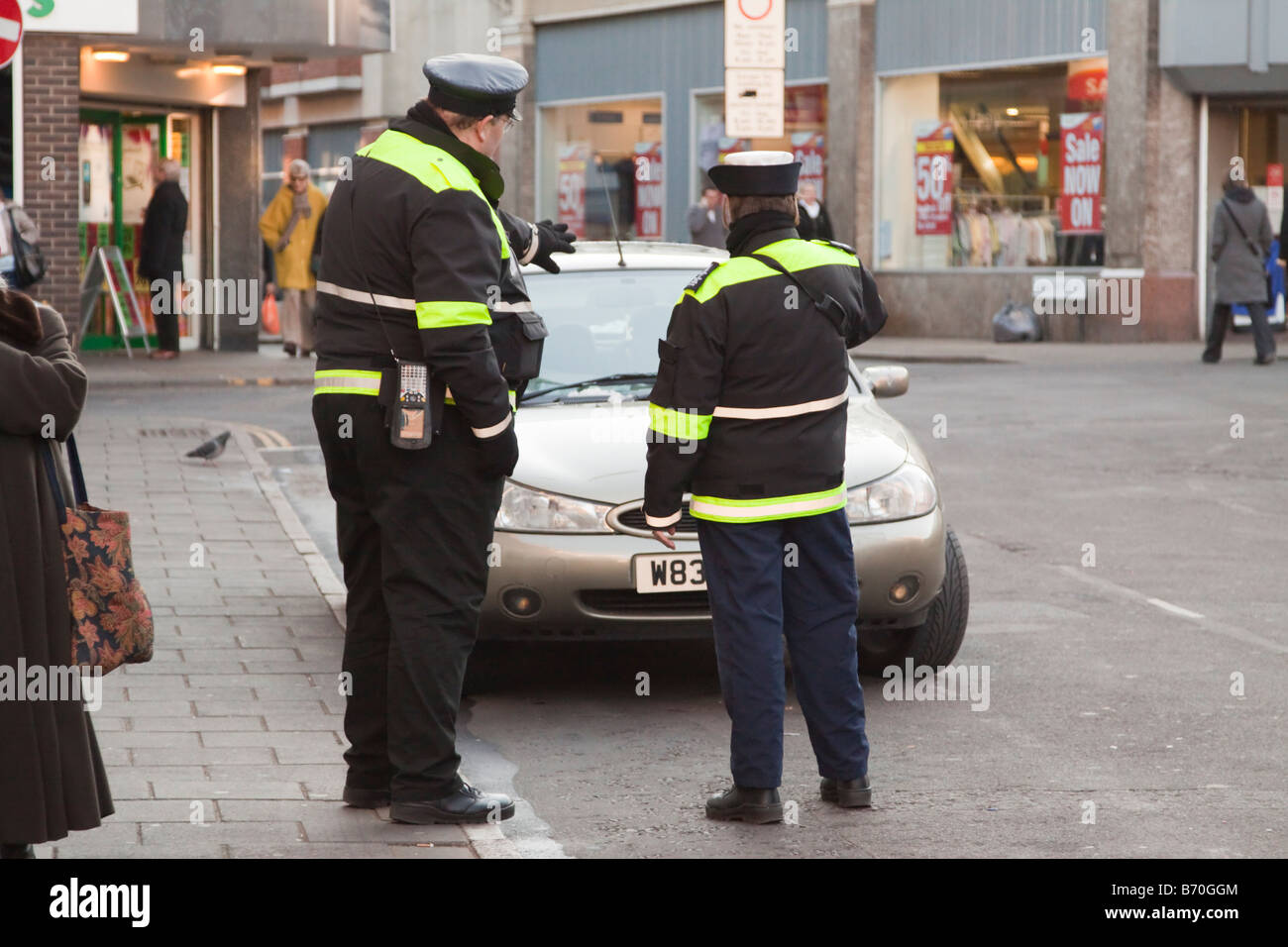 Il traffico di due operai in piedi da una vettura parcheggiata illegalmente per i quali hanno rilasciato un biglietto. Foto Stock