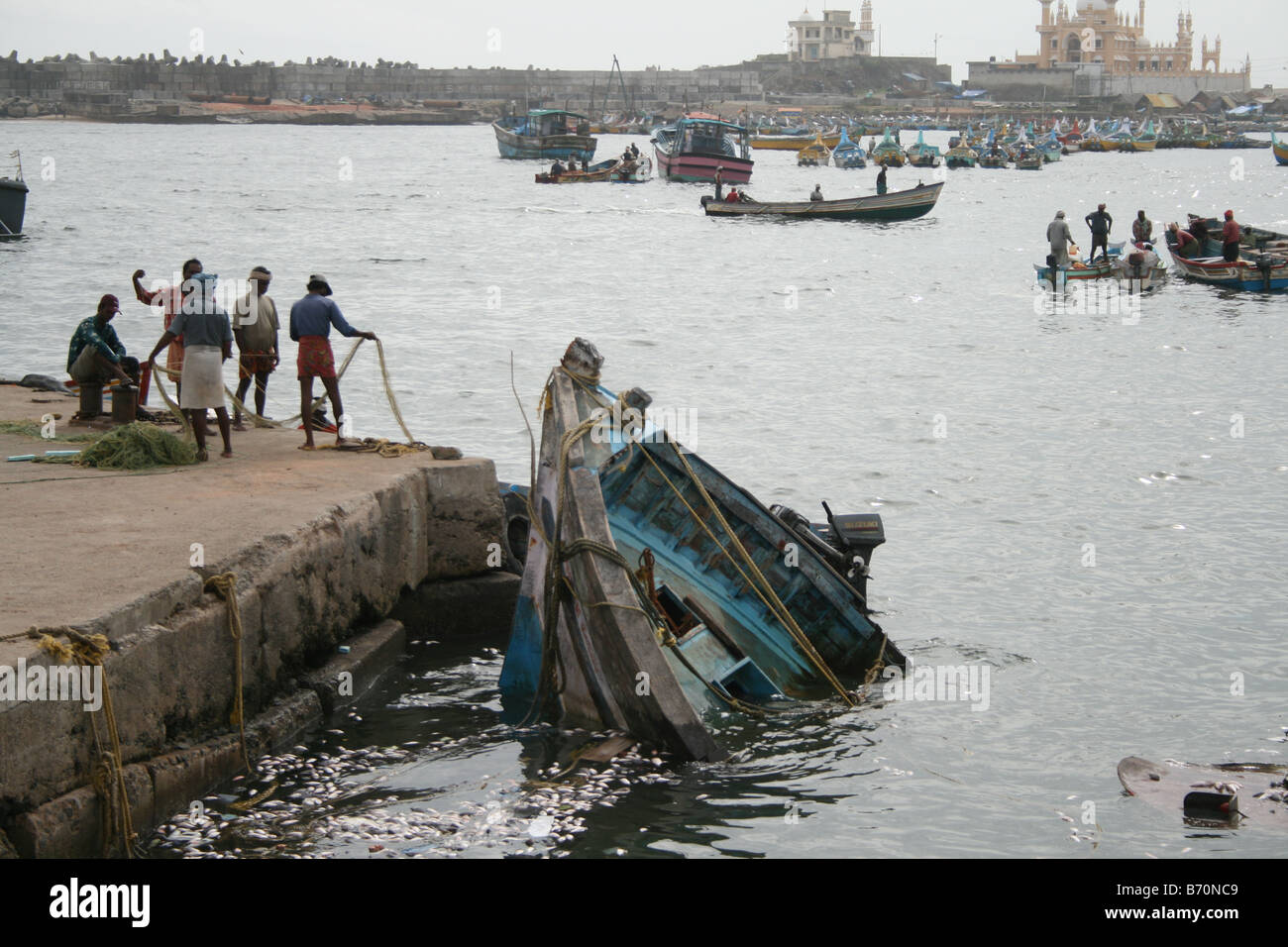 Un gruppo di pescatori locali il tentativo di salvataggio del naufragio barca nel porto di pesce dopo aver scoperto che non vi era alcun proprietario per esso. Foto Stock