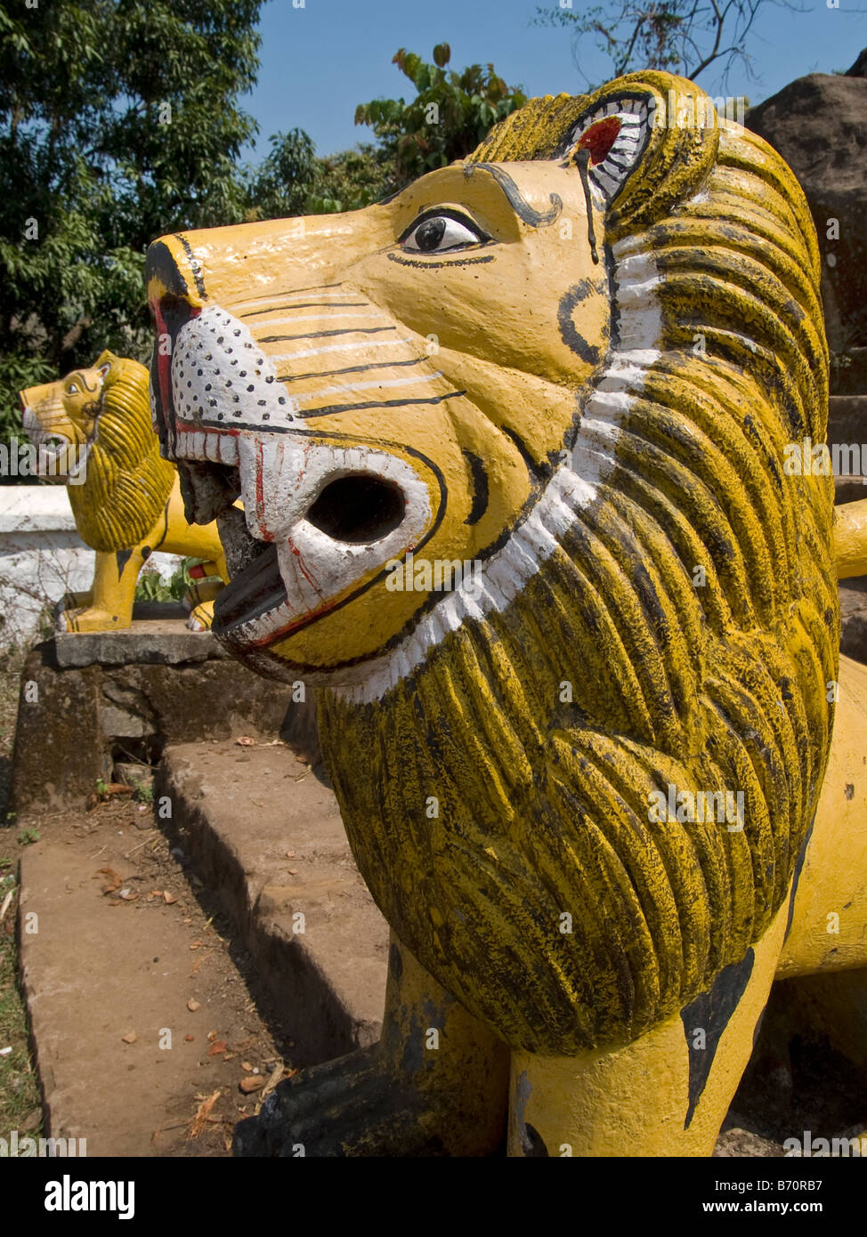Ingenuo dipinto in giallo lions custode fiancheggiano il passi per un tempio indiano Foto Stock