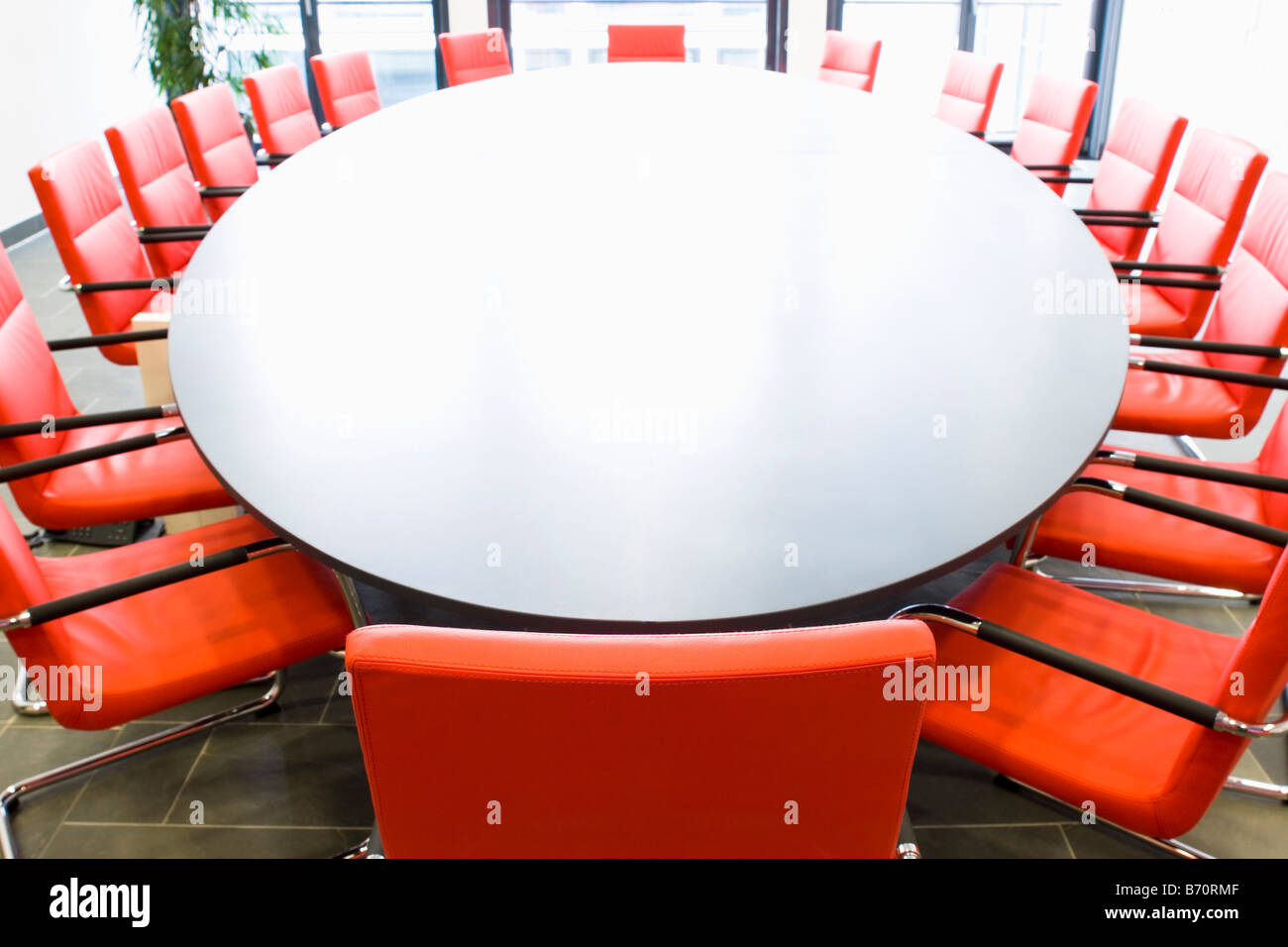 Sala riunioni con sedie rosse e tavolo ovale Focus sulla sedia in primo piano Foto Stock