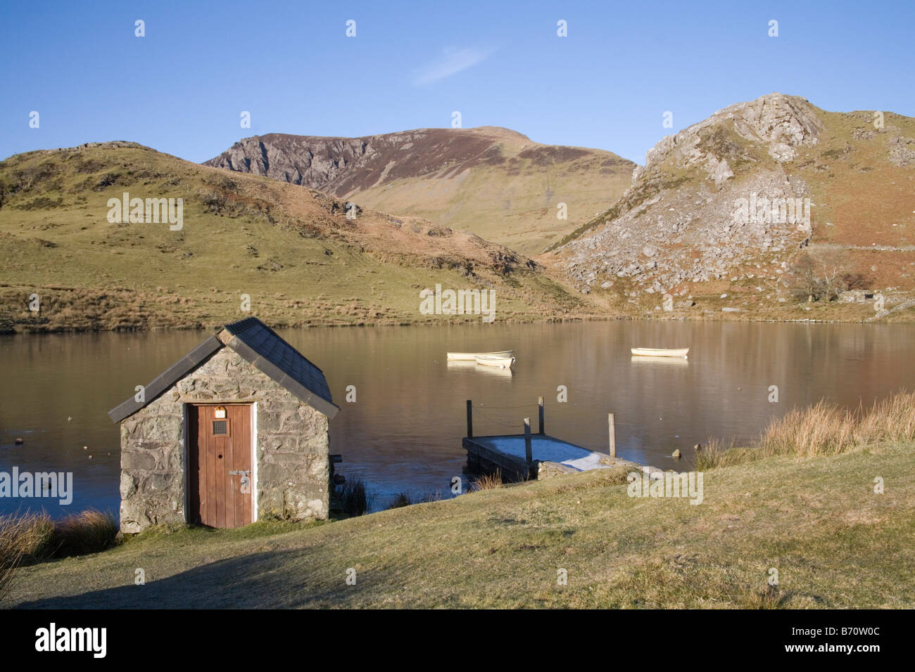 Rhyd Ddu Gwynedd Galles del Nord gennaio guardando attraverso la pesca congelati lago Llyn y Dywarchen con una casa-barca e tre canottaggio Foto Stock