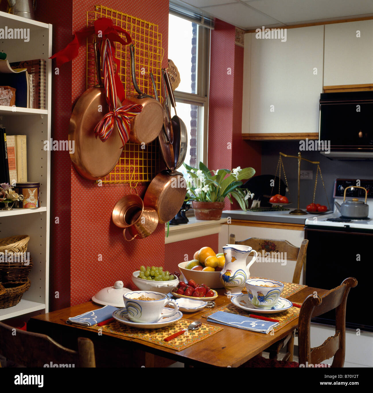 Pentole in rame sulla rastrelliera metallica al di sopra di piccolo tavolo  di legno fissato per il pranzo in rosso la cucina con le unità bianche Foto  stock - Alamy