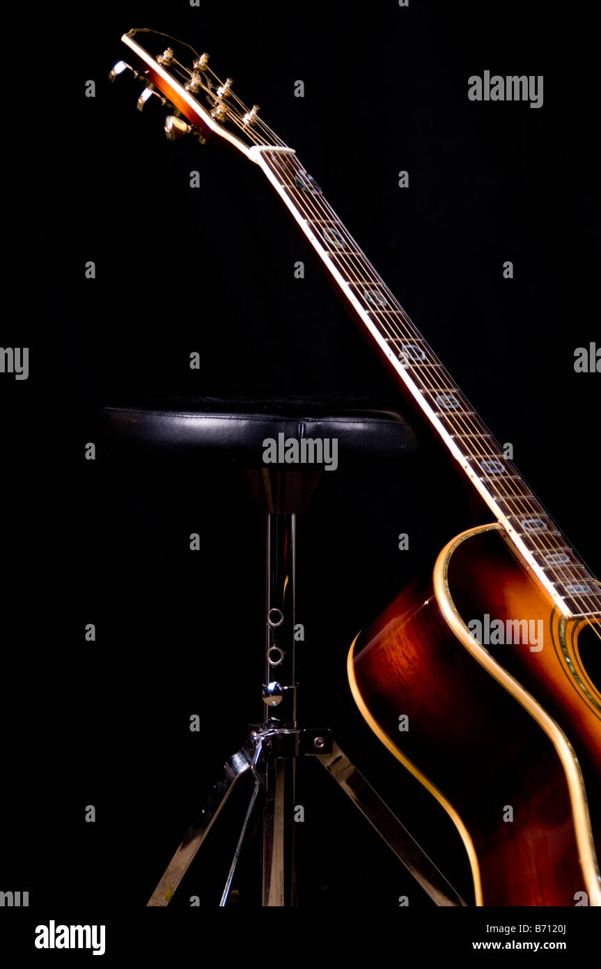 Chitarra acustica appoggiata contro il batterista è uno sgabello Foto Stock