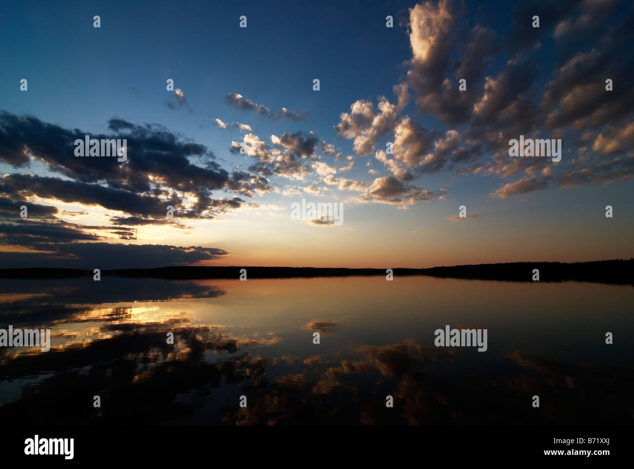 Bel tramonto dal lago calmo con soffici nuvole contro inscurimento cielo blu, Asikkala, Finlandia Foto Stock