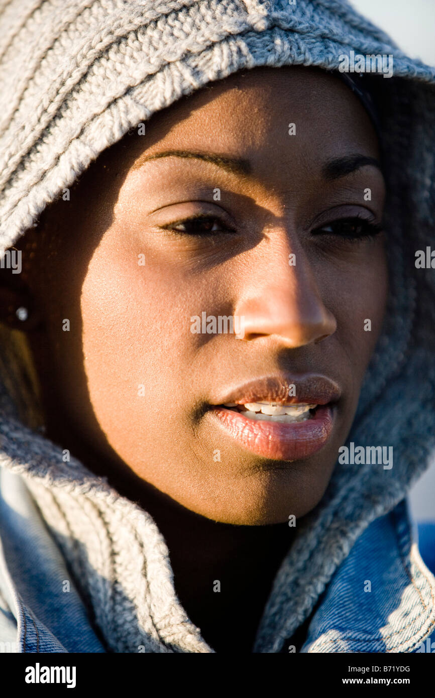 Close-up del giovane americano africano donna che indossa top con cappuccio in piedi in spiaggia Foto Stock