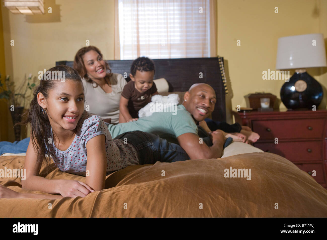 Felice famiglia americana africana sdraiato sul letto a guardare la TV Foto Stock