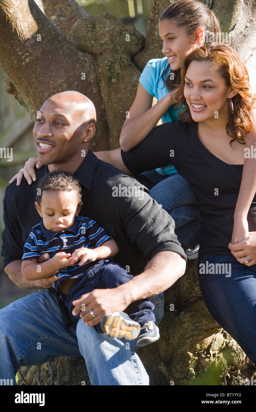 Felice famiglia americana africana seduti intorno ad albero in cortile Foto Stock
