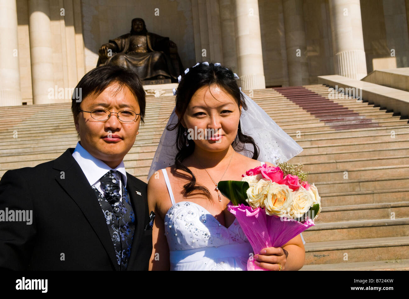 Gli sposi posano per una foto davanti alla statua di bronzo di Chingis Khan. Sukhbataar squear, Ulan Bataar Foto Stock