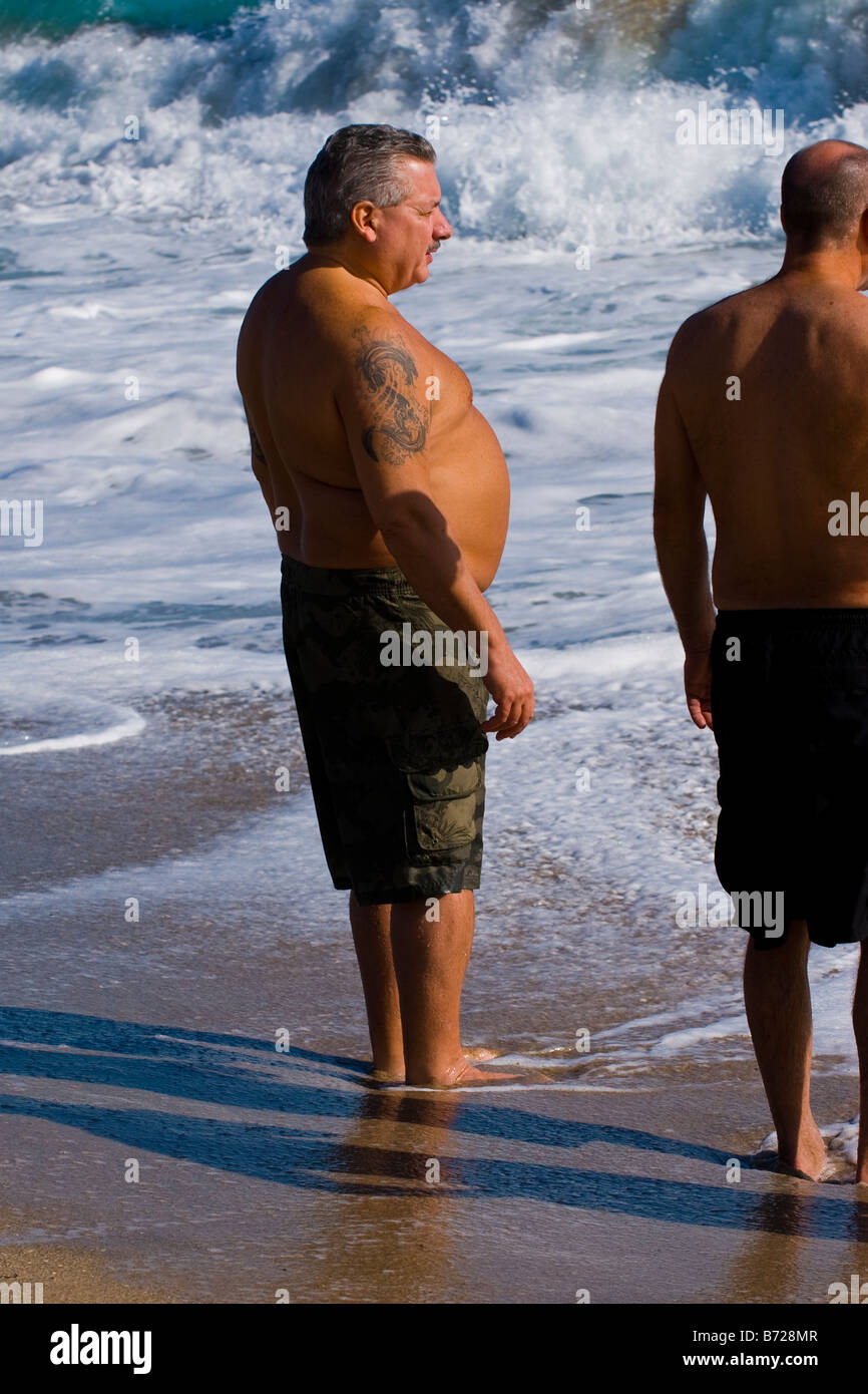 Palm Beach Shores , Florida , portly uomo di mezza età con tatuaggio sulla sabbia in sun in riva al mare kayak Foto Stock