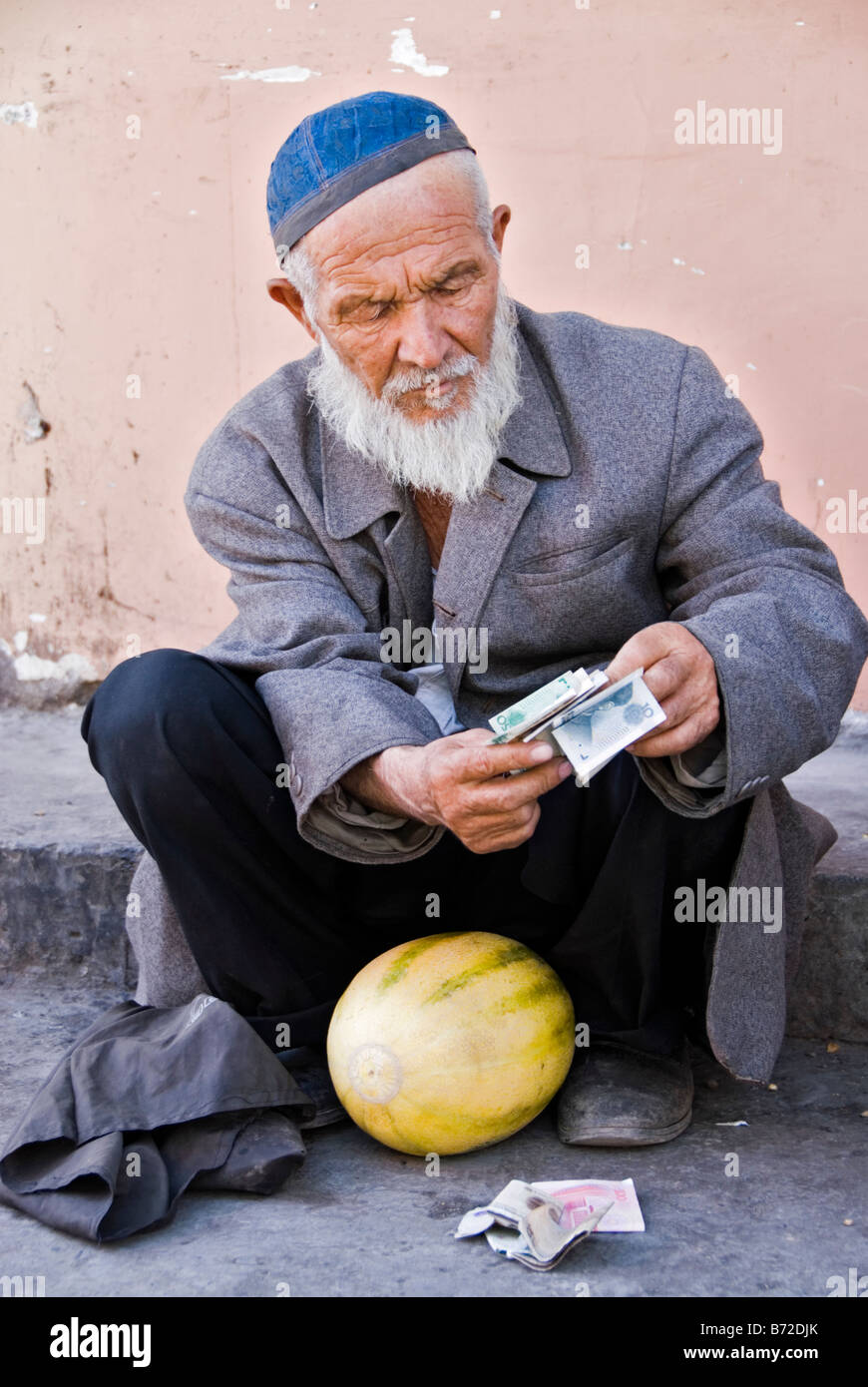 Uomo con melone conteggiare denaro Kashgar nello Xinjiang Cina Foto Stock