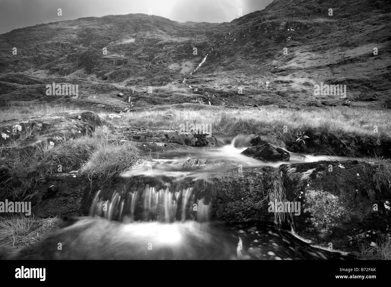 Foto in bianco e nero di un flusso in uscita verso il basso di una collina nella Ballaghbeama Gap, Ring of Kerry, Irlanda Foto Stock