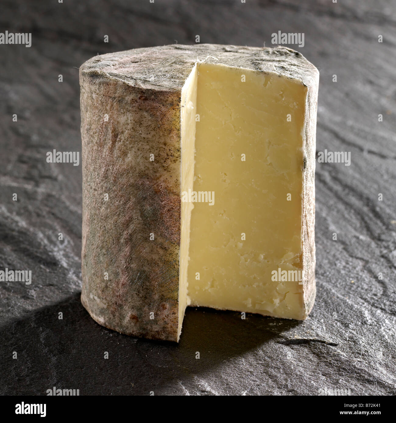 Taglio tradizionale di formaggio cheddar in forme intere Foto Stock