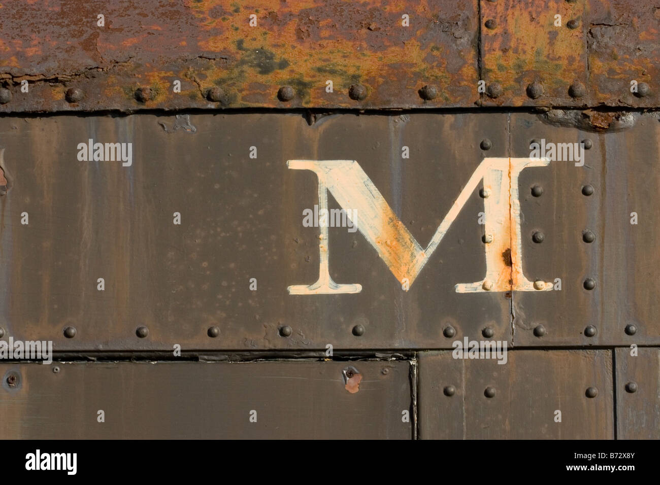 La lettera M sul lato del vecchio arrugginito auto in treno Foto Stock