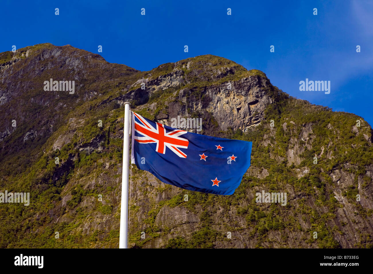 Nuova Zelanda bandiera sventolare nel vento a Milford Sound. Nuova Zelanda, Isola del Sud, il Parco Nazionale di Fiordland, Milford Sound. Foto Stock