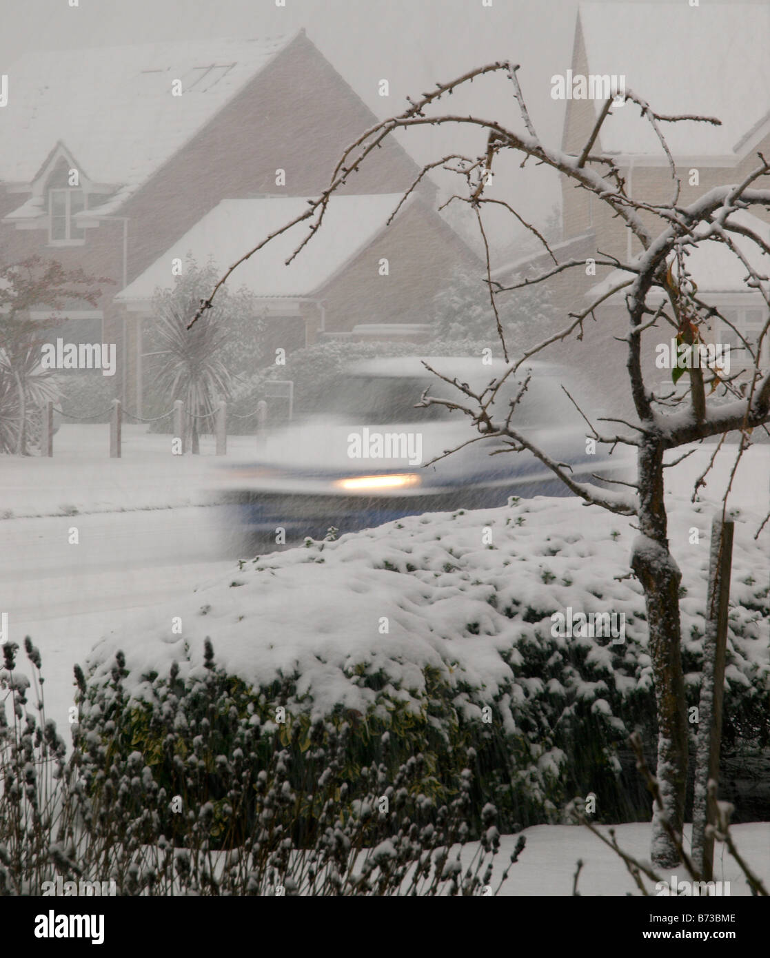 La vita styleBlue auto con luci accese e coperte di neve in movimento attraverso la nevicata nel Norfolk alloggiamento station wagon, bianco inverno da Foto Stock