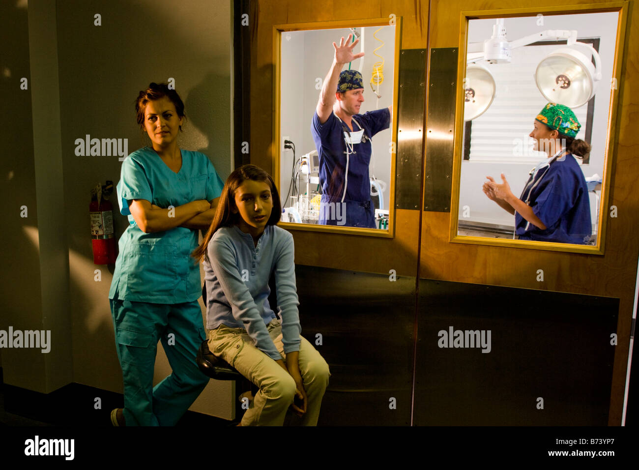 Ragazza e un assistente medico attendere fuori porta chiusa della sala operatoria Foto Stock
