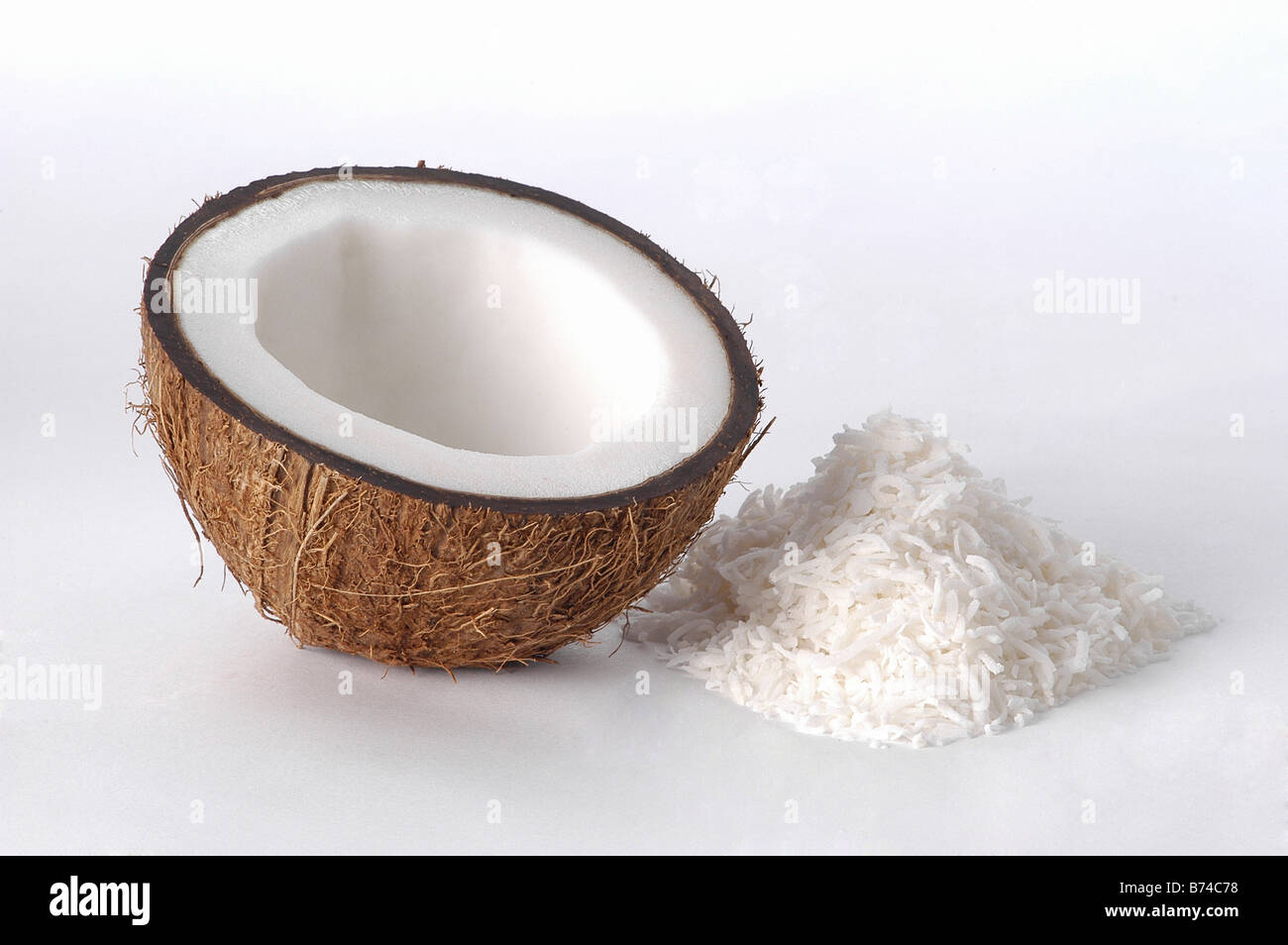 Una mezza noce di cocco con pila di noce di cocco essicata Foto Stock