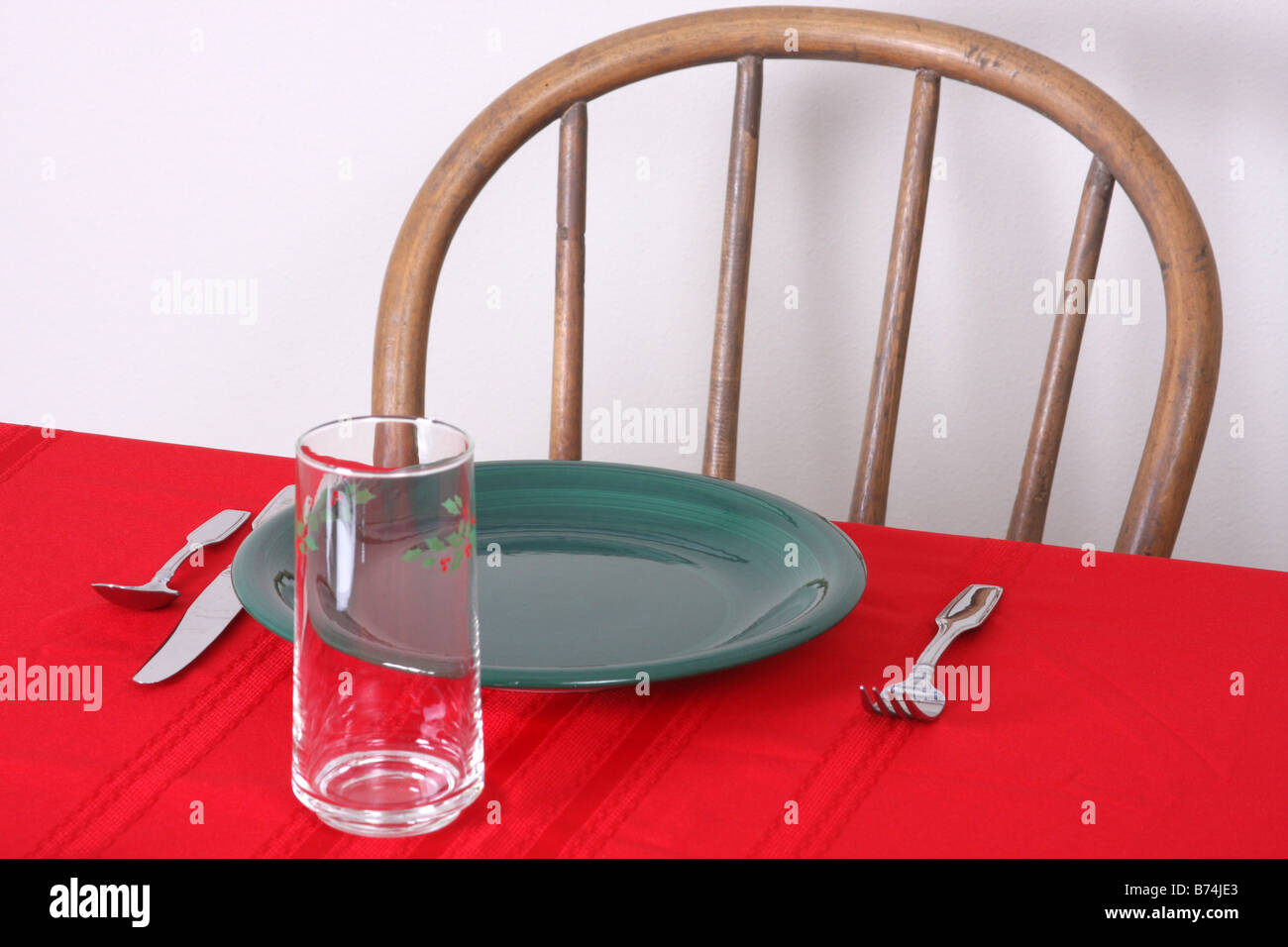 Una tovaglia rosso e verde piastra con una vacanza in vetro Impostazione tabella Foto Stock