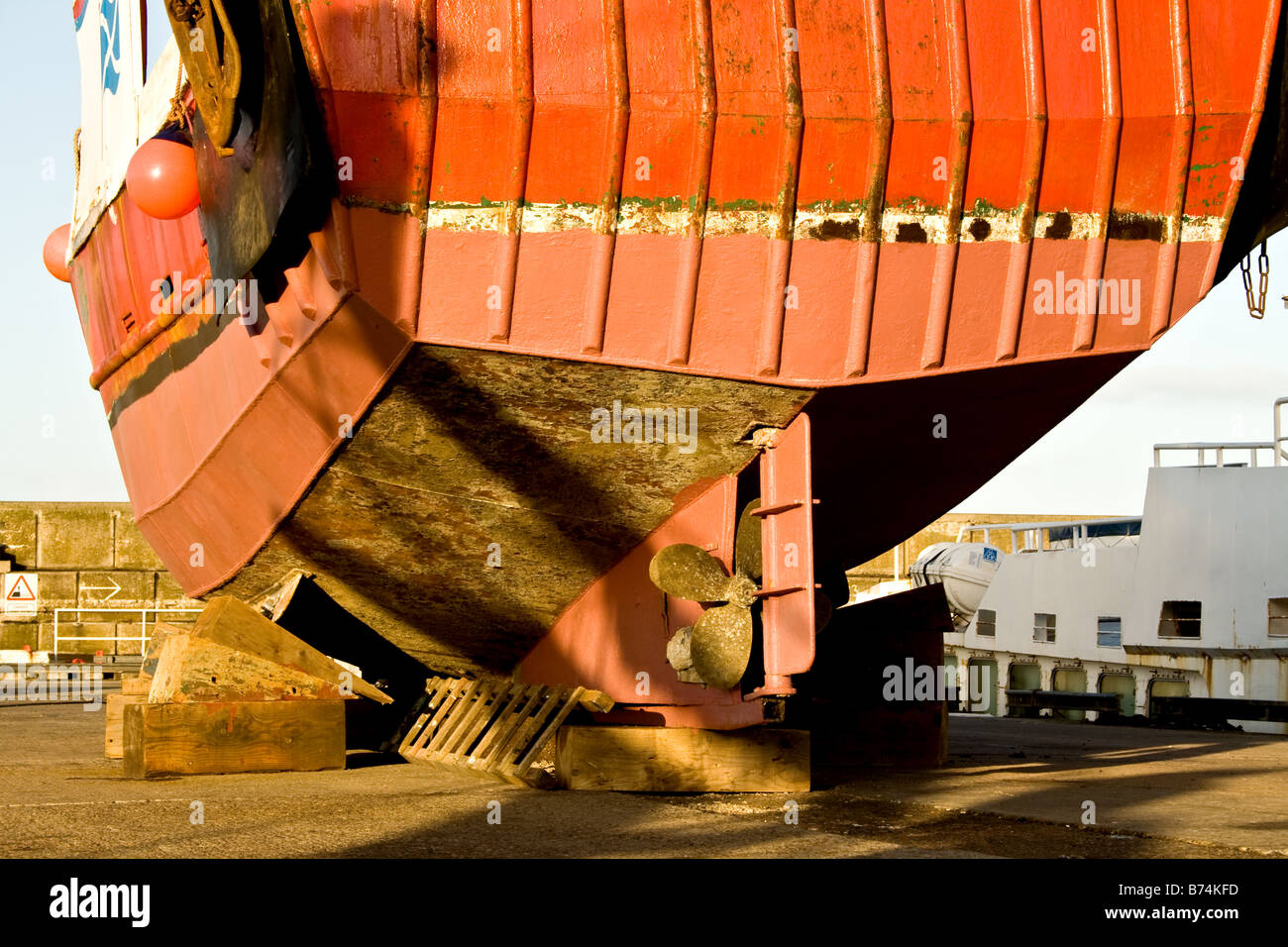 Fondo di un arancione la barca di salvataggio su drydock con un propulsore fuori dall'acqua. Foto Stock