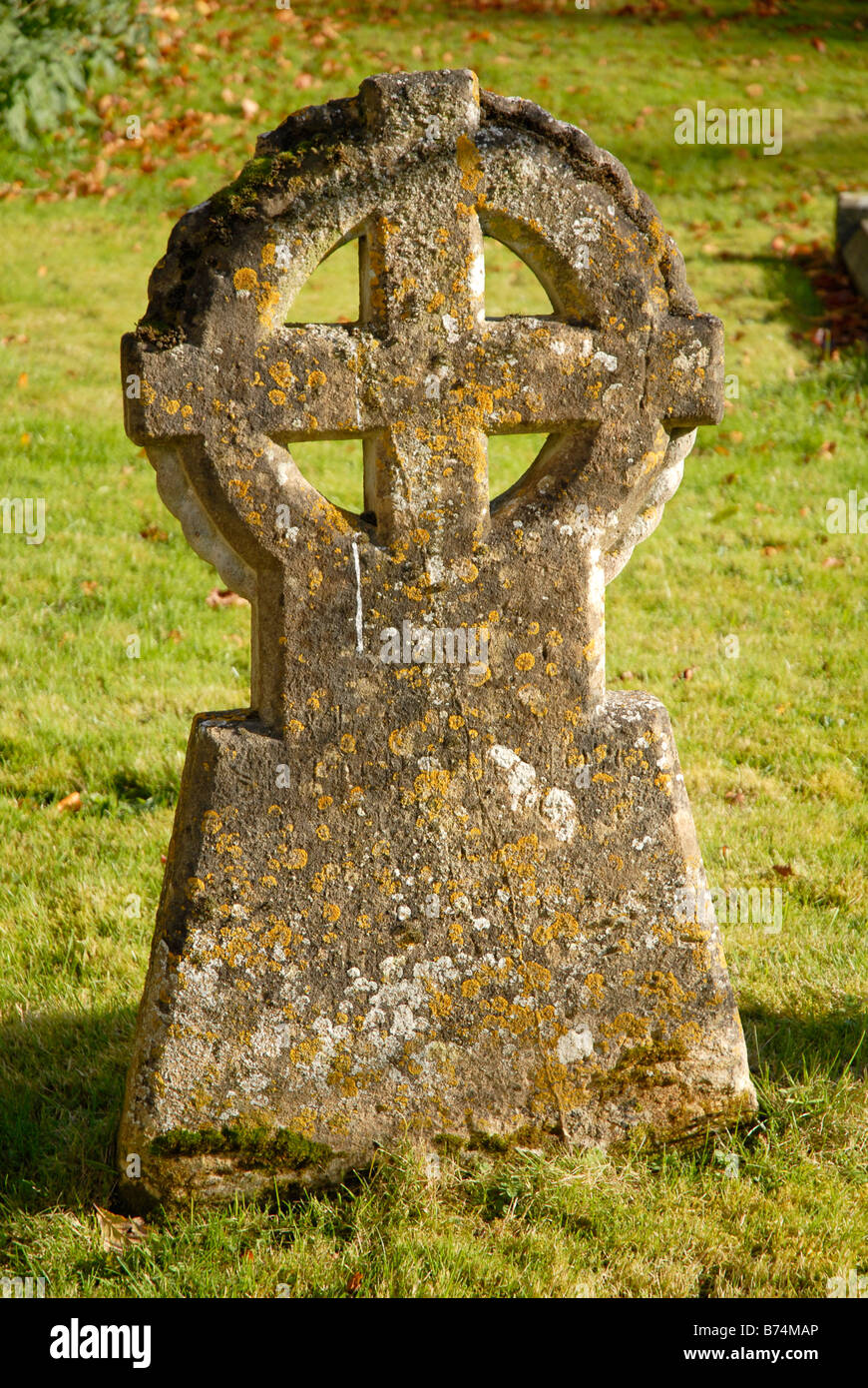 Antica tomba di pietra, in un cimitero con la croce racchiuso in un cerchio e licheni crescono su di esso. Foto Stock