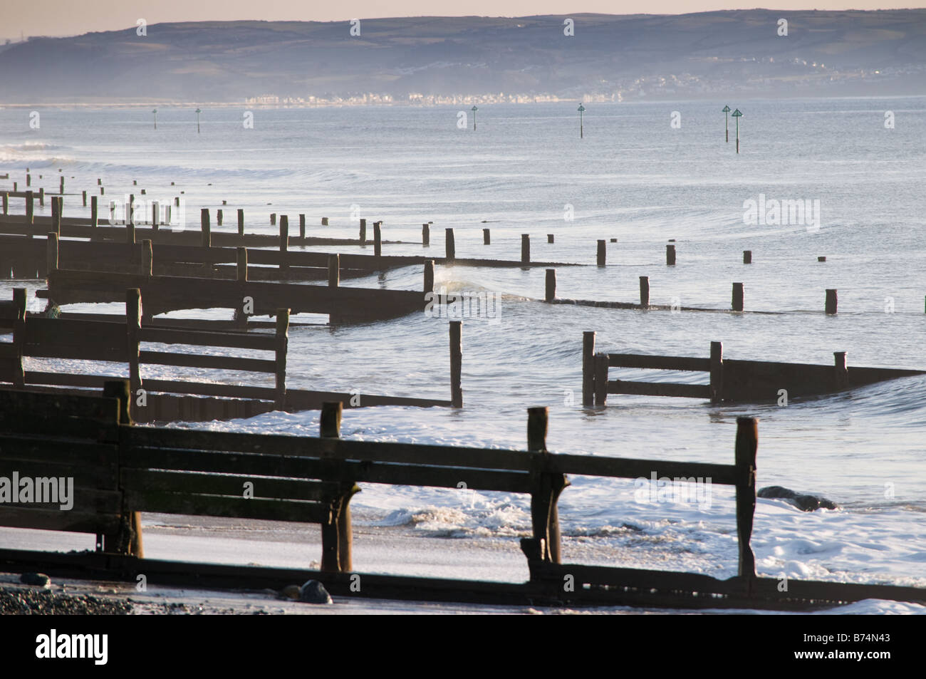 Righe di pennelli in legno le difese di mare sulla spiaggia di Tywyn west wales guardando verso sud, che necessitano di riparazione, rotto Foto Stock